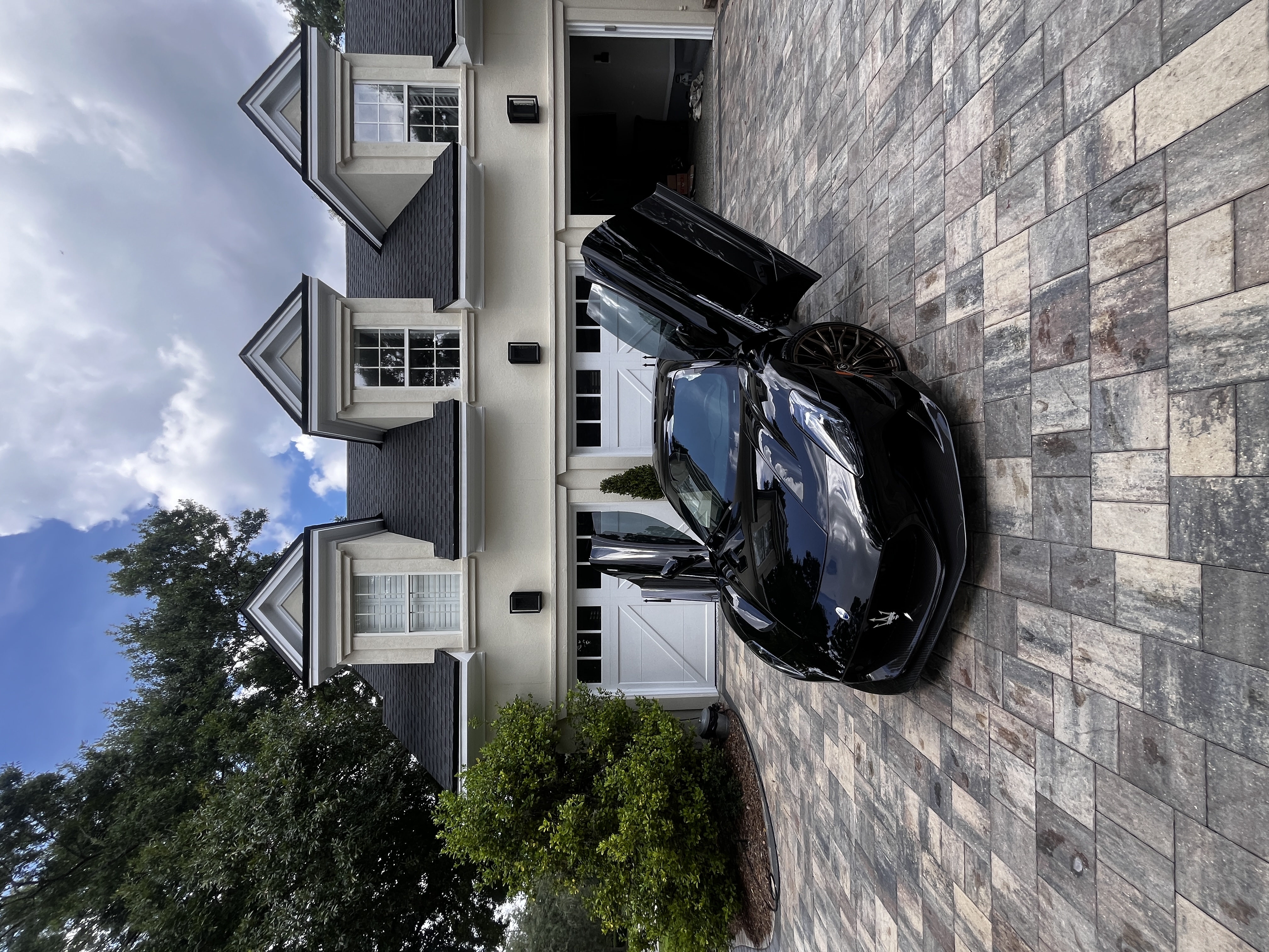 Black Maserati freshly detailed with doors open on a paver driveway